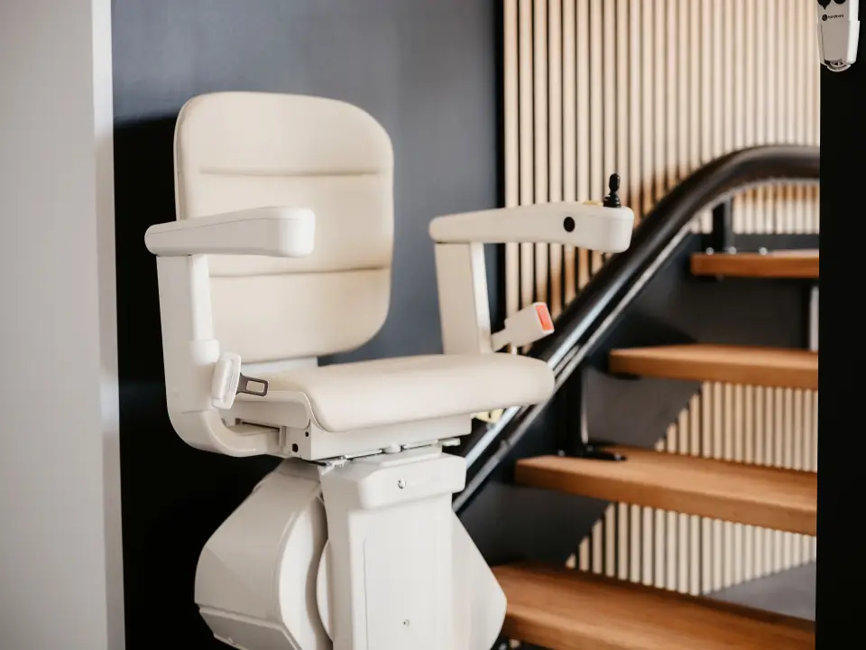 Sitzlift mit hellem Polstersitz an einer Holztreppe