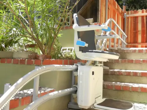Treppenlift mit Kurvenschiene an einer Außentreppe aus Klinker
