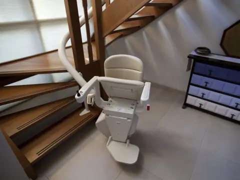 Treppenlift am Fuß einer gewendelten Holztreppe