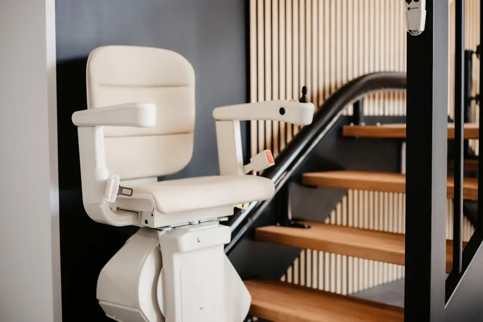Sitzlift mit hellem Polstersitz an einer Holztreppe im Showroom in Nordhorn